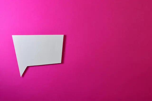 Plain pink background with paper cutout of rectangular speech bubble